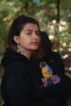 portrait en extérieur d'une artiste avec mise en valeur du produit sweatshirt imprimé, éclairé par lumière naturelle