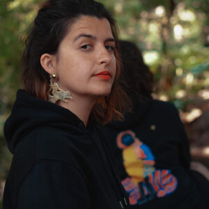 portrait en extérieur d'une artiste avec mise en valeur du produit sweatshirt imprimé, éclairé par lumière naturelle