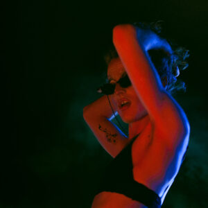 portrait d'une dragqueen en train de danser, éclairée aux néons rouge et bleu