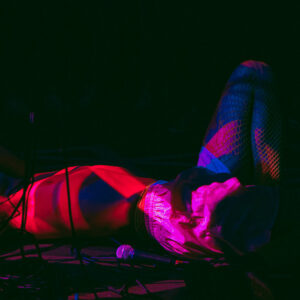 photo de concert d'une personne couchée au sol, éclairée à la lumière rouge